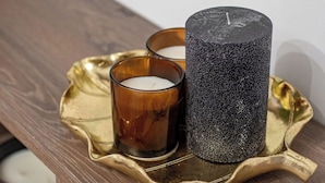 A tray with a candle and a textured container on a wooden surface. - Central Square Haven B (București)