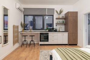 Uma cozinha compacta com forno embutido, micro-ondas e pia. Há dois bancos e uma janela acima do balcão.