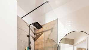 Een moderne badkamer met een douchecabine van glas, een ronde spiegel en een waskom.