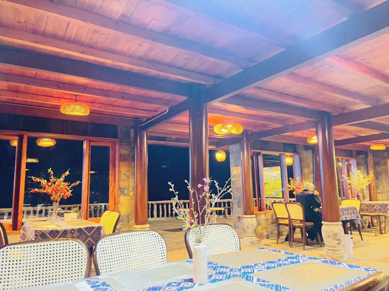 An outdoor restaurant with tables and chairs, wooden beams, and decorative lighting.