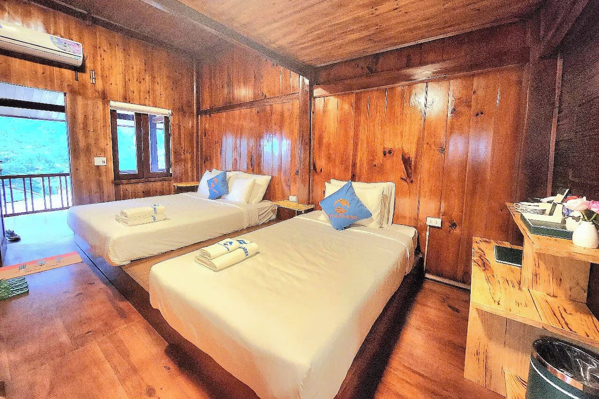 A wooden cabin with two beds, a small table, and a window.