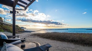 Ein Sitzbereich am Strand mit Blick auf den Ozean und einem Pier im Hintergrund.