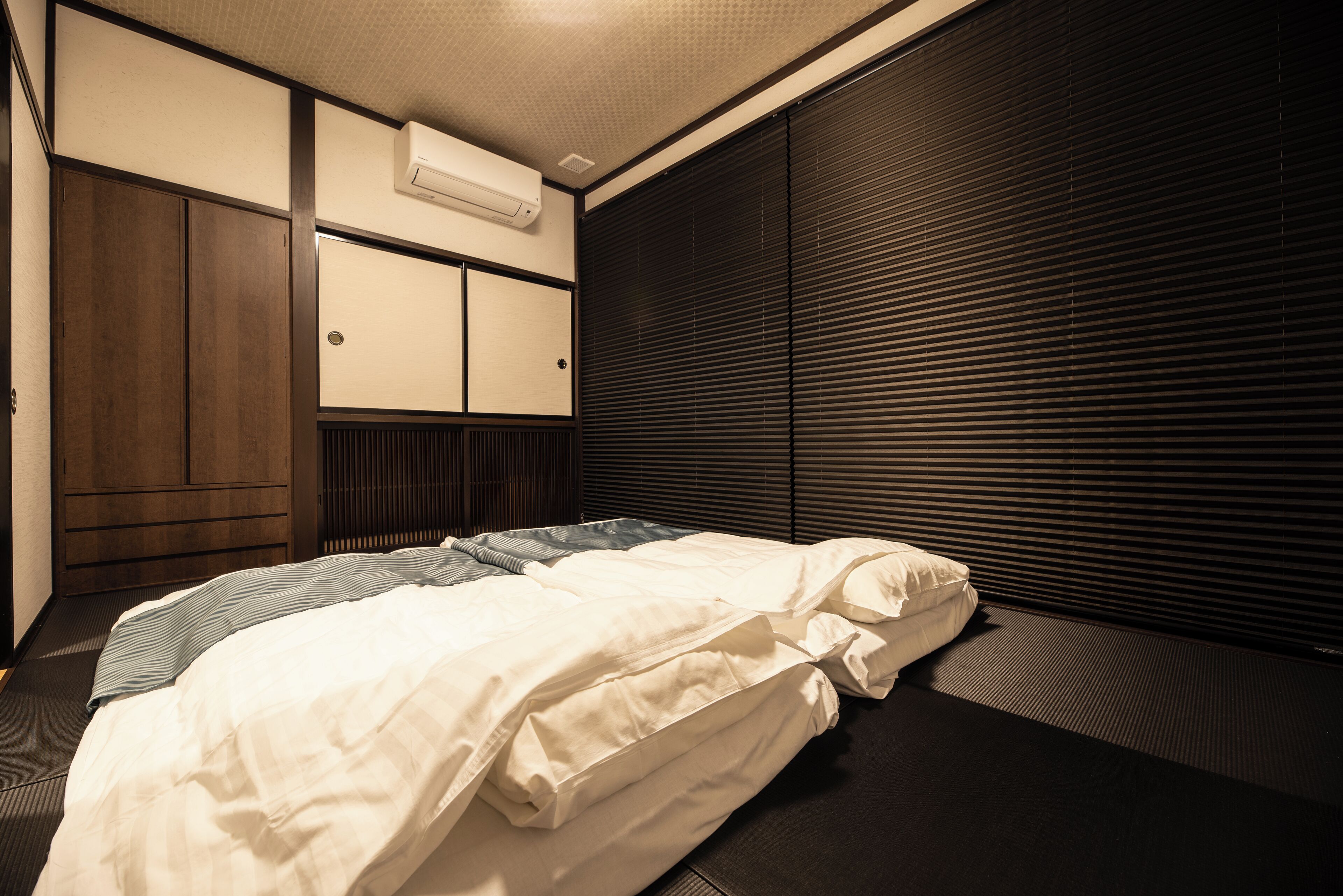 Ein Hotelzimmer mit Bett, Kleiderschrank und einem Fenster mit Jalousien.