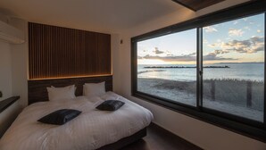 Ein Schlafzimmer mit einem großen Fenster, das Meerblick bietet, und einer Holzbalkendecke.