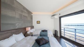 Une chambre d’hôtel avec deux lits, une grande fenêtre donnant sur la mer et un design moderne.