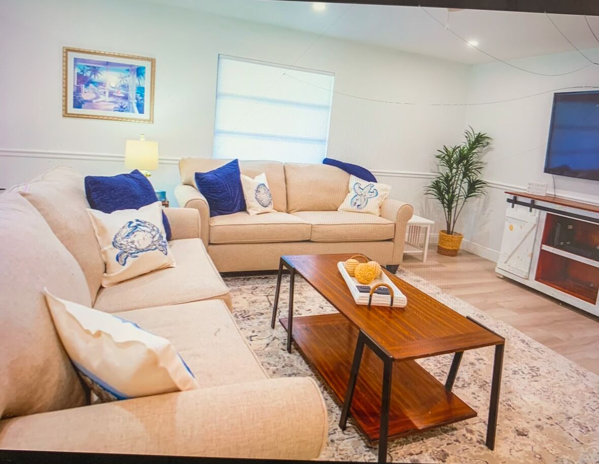 Un salon avec un canapé beige, une table basse en bois et un téléviseur en arrière-plan.