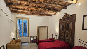 Ein Zimmer mit zwei Betten, Holzboden, Fenster und Tür.