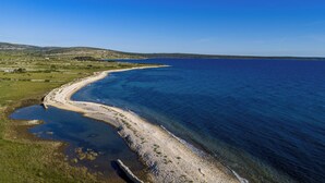 A coastal landscape with a clear view of the sea, a sandy beach, and distant hills. - Villa Maslina: Rustic villa in an olive grove facing a bird sanctuary  (Kolan)