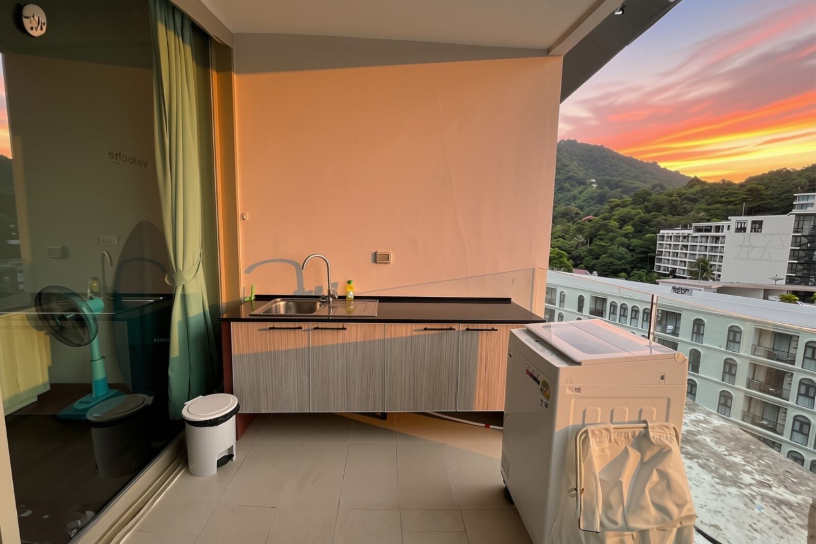 A balcony with a sink, a fan, and a washing machine.