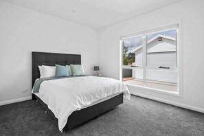Relax in a spacious bedroom with a large bed and a window offering a view of the surrounding area.