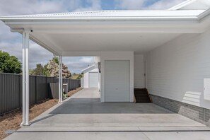 Step outside to an outdoor space with a concrete floor and metal railing.