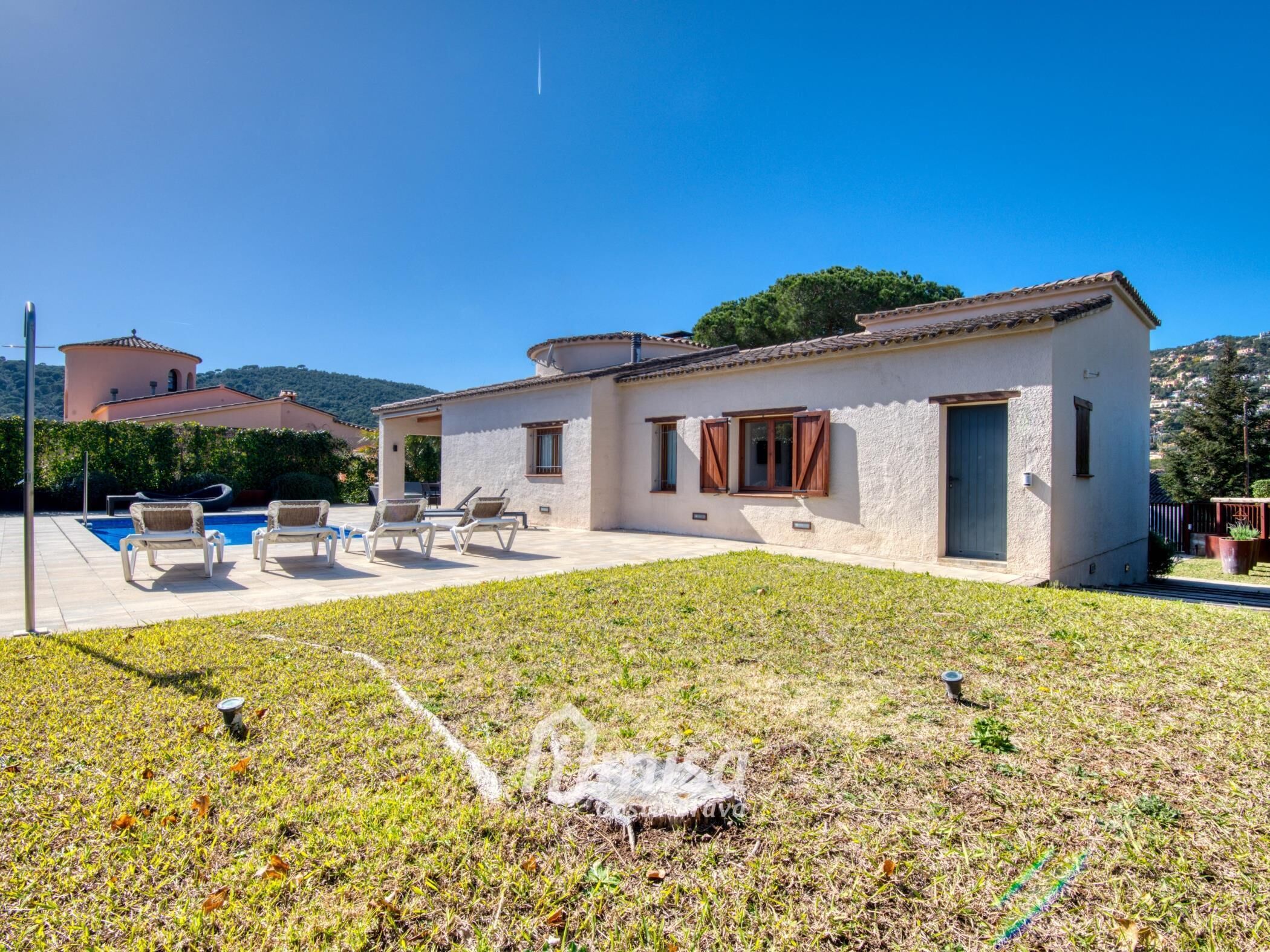 A single-story house with a pool, outdoor seating, and a grassy yard.