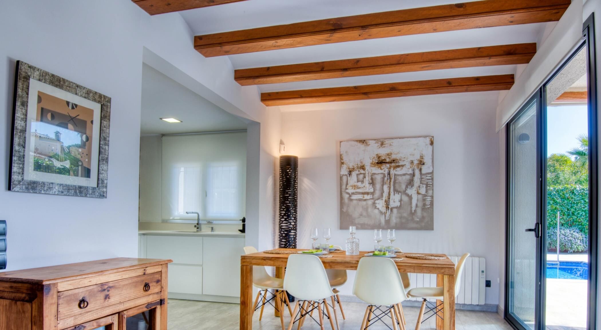 Un moderno comedor con una mesa de madera, sillas blancas y un cuadro abstracto grande en la pared.