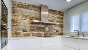 A modern kitchen with a stone backsplash, stainless steel appliances, and a window providing natural light.