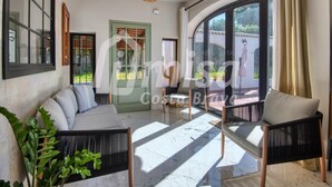 A spacious living area with a sofa, chairs, a large window, and a door leading outside.