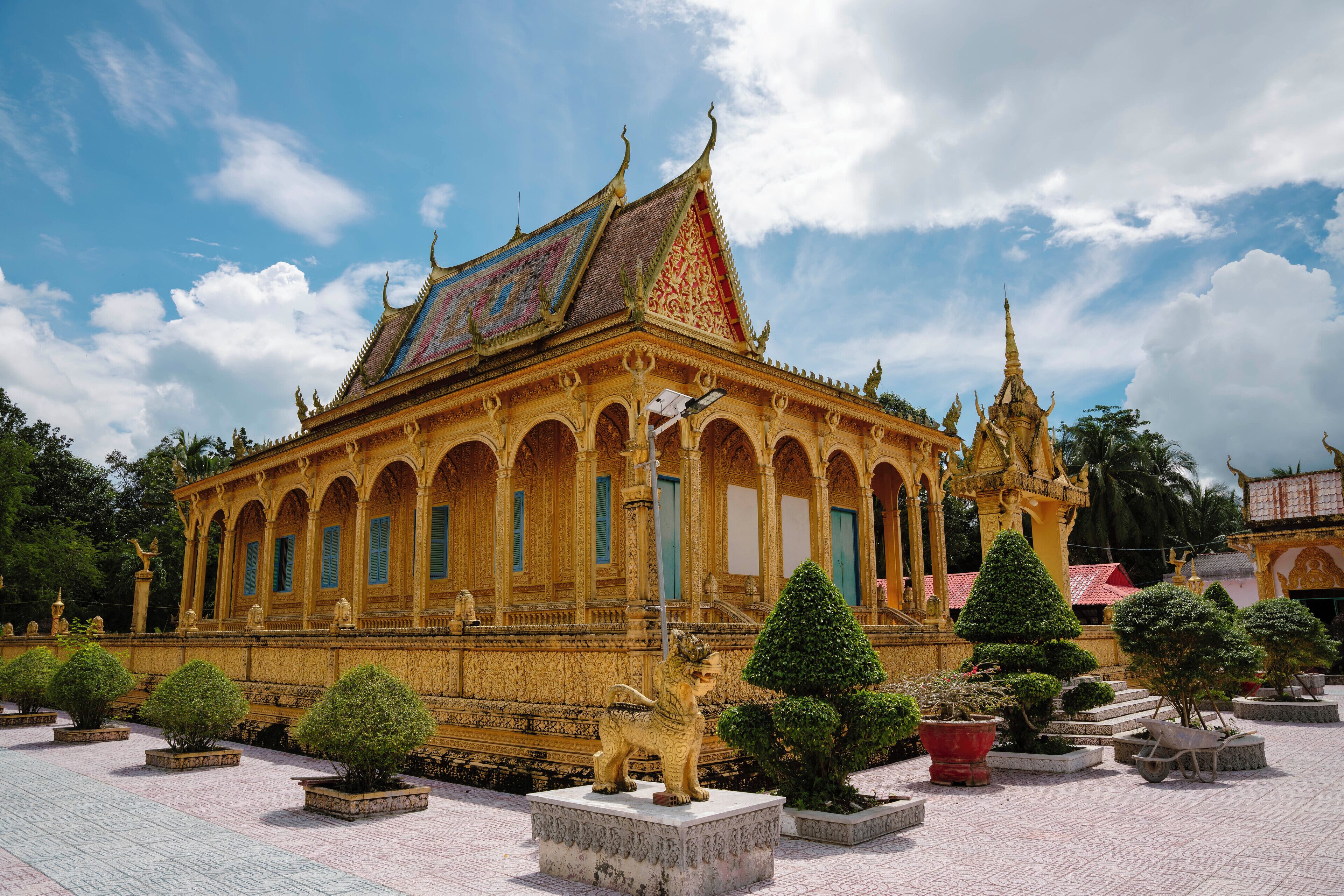 A traditional temple with ornate architecture, a central statue, and a well-maintained garden.