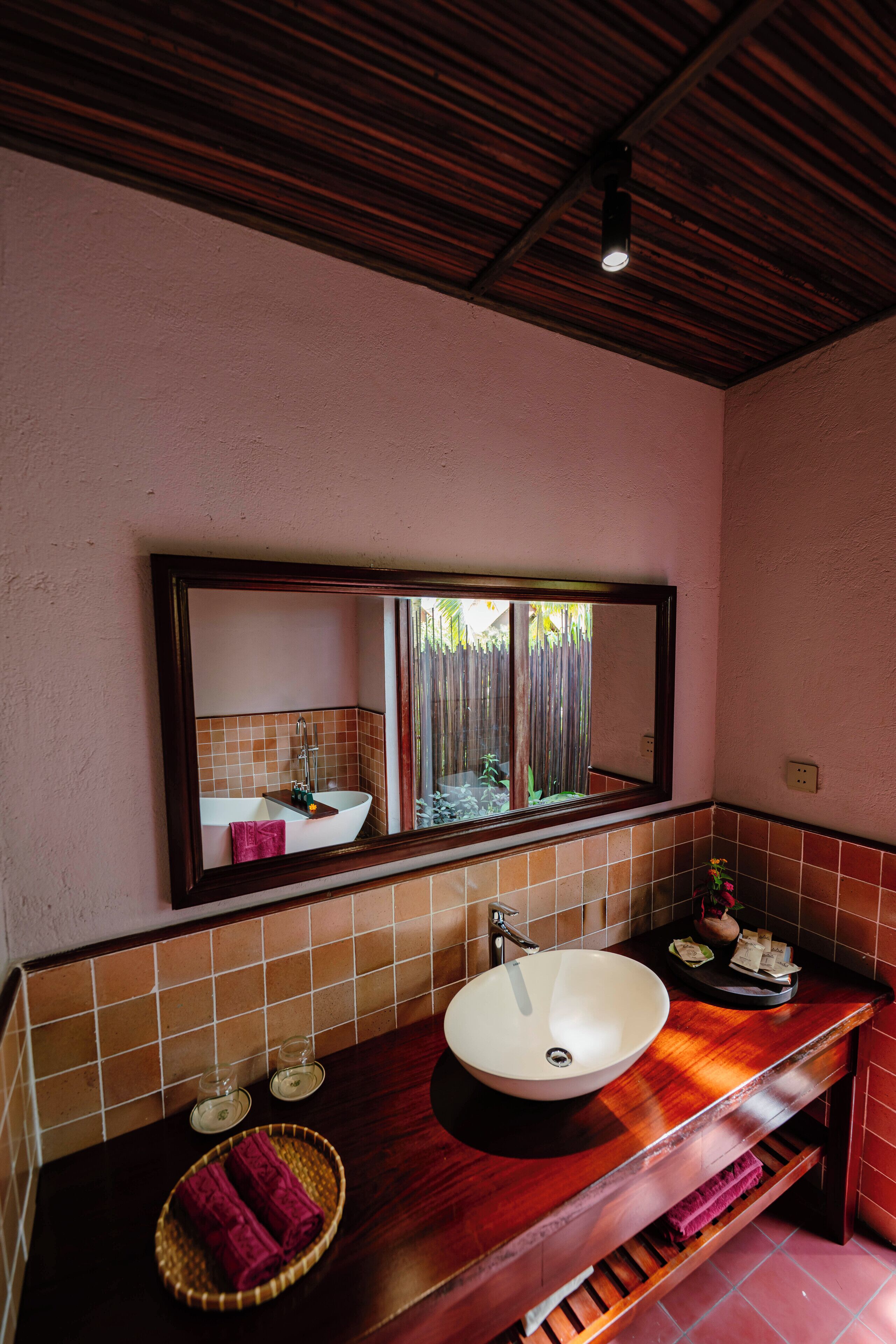 A bathroom with a wooden vanity, a white sink, and a mirror above it.