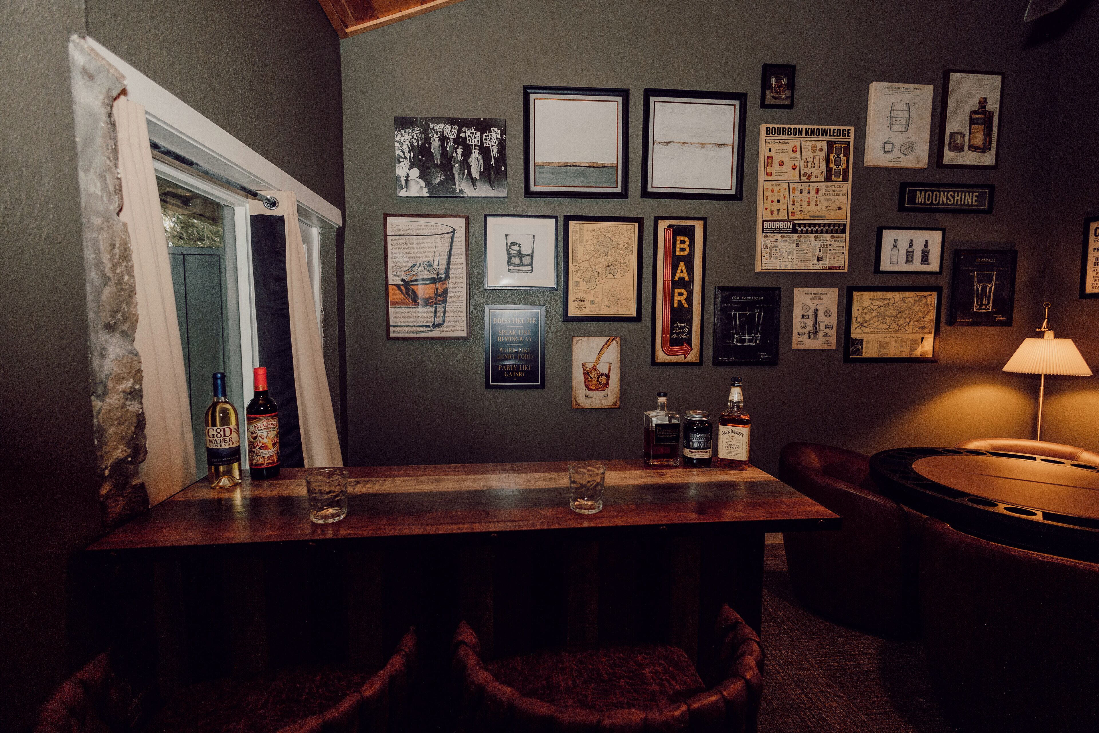 A bar area with a wooden table, chairs, and various framed pictures on the wall.