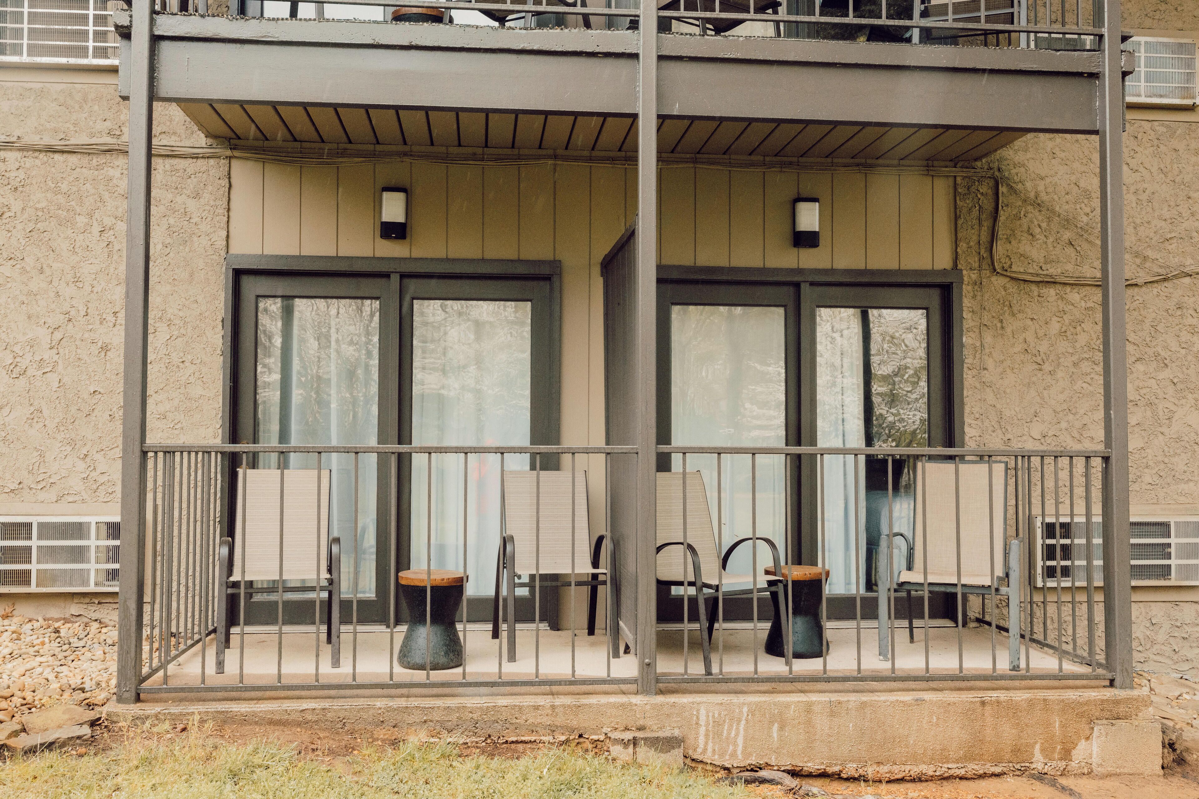 A two-story building with a balcony featuring outdoor seating and a metal railing.