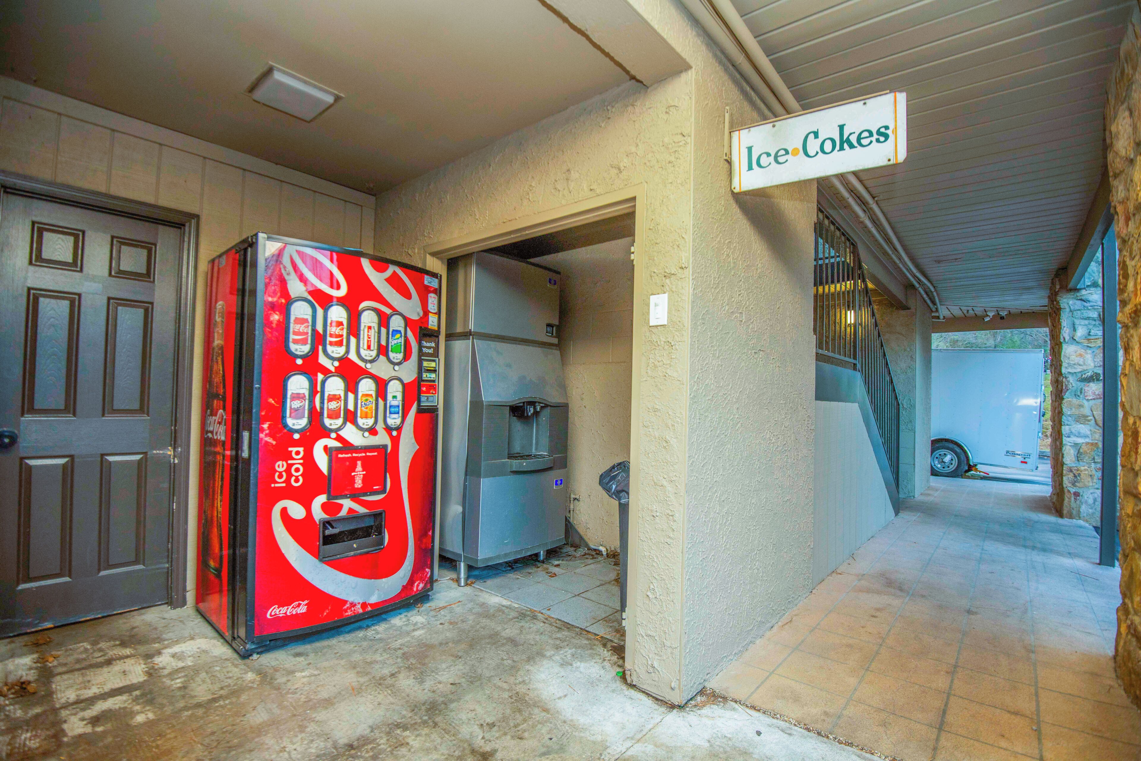 Un distributeur automatique de Coca-Cola se trouve à l’extérieur d’un bâtiment, sur lequel est apposée une pancarte indiquant « Coca-Cola bien frais ».