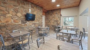 Un restaurante con paredes de piedra, techo de madera y varias mesas y sillas.
