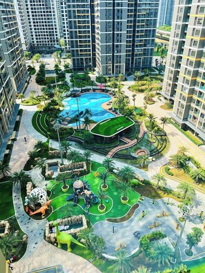 A high-rise residential building with a central courtyard featuring a swimming pool, playground, and landscaped areas. - Lyshing Apartment in Vinhomes Grand Park (Ho Chi Minh City)