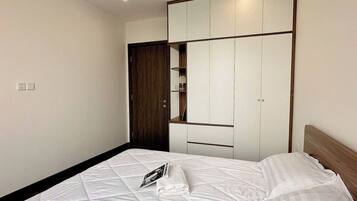 A bedroom with a bed, a wardrobe, a mirror, and a ceiling light.