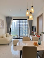 Uma sala de estar moderna com sofá, mesa de jantar, cadeiras e uma janela grande com vista para a cidade.