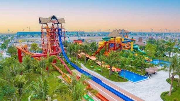 A water park with multiple slides and pools, surrounded by palm trees and a clear sky. - Lyshing Apartment in Vinhomes Grand Park (Ho Chi Minh City)