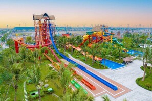 Un parque acuático con múltiples toboganes y piscinas, rodeado de palmeras y un cielo despejado.