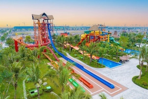 Um parque aquático com vários toboáguas e piscinas, cercado por palmeiras e um céu limpo.