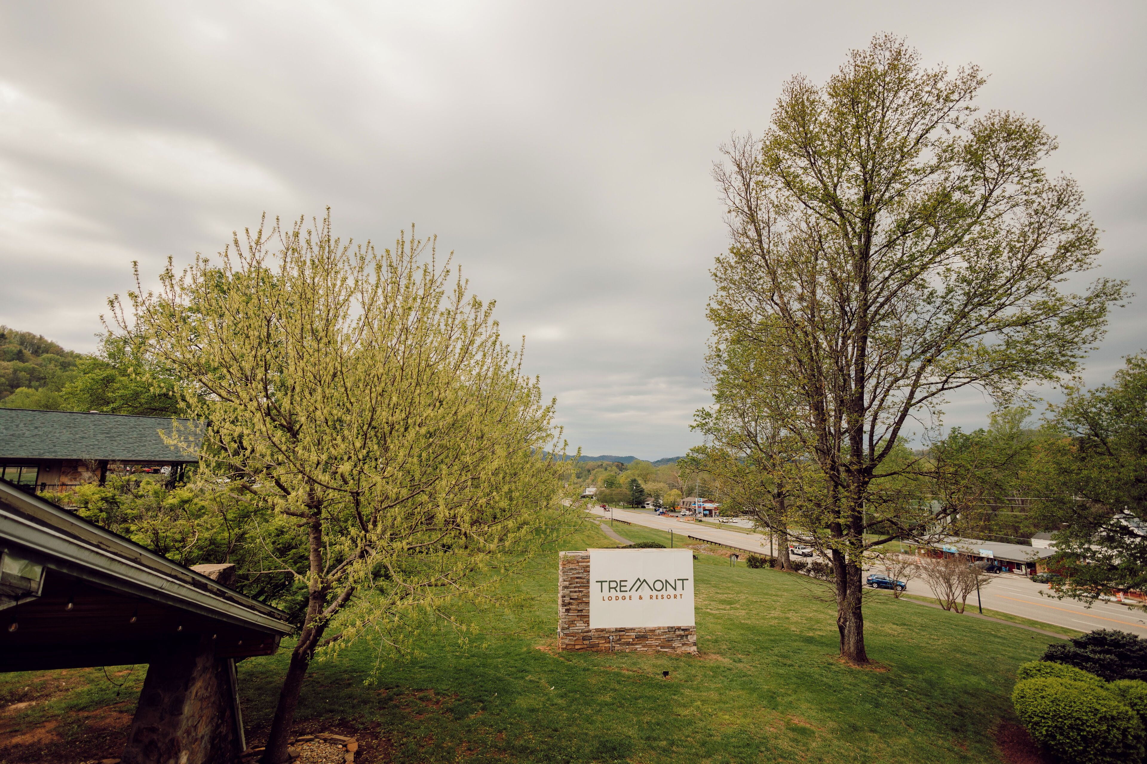 A sign for Tremont Lodge & Resort with a view of the surrounding landscape and a road in the background.