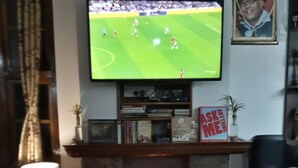 Un soggiorno con camino, televisore montato sopra e un quadro appeso al muro.