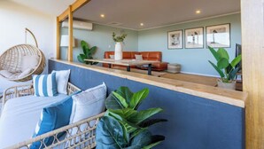 Une pièce comprenant un lit, un fauteuil suspendu, un canapé et un coin repas avec une table et des chaises.