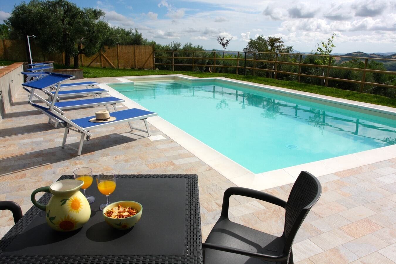 A swimming pool with lounge chairs and a table with breakfast items.