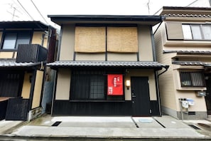 Un edificio japonés tradicional con entrada negra, letrero rojo y tejado de tejas.