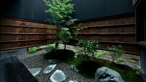 A modern interior with a wooden slatted wall, a small tree, and a gravel pathway. - Miro Hachijo Genmachi BeTei (Kyoto)