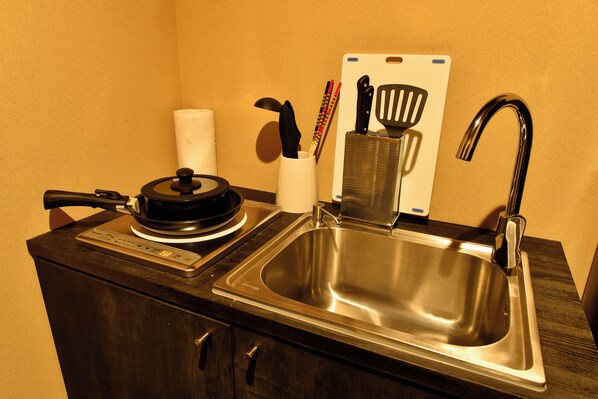 A kitchen with a stainless steel sink, a coffee maker, and a set of knives and spatulas on the counter.