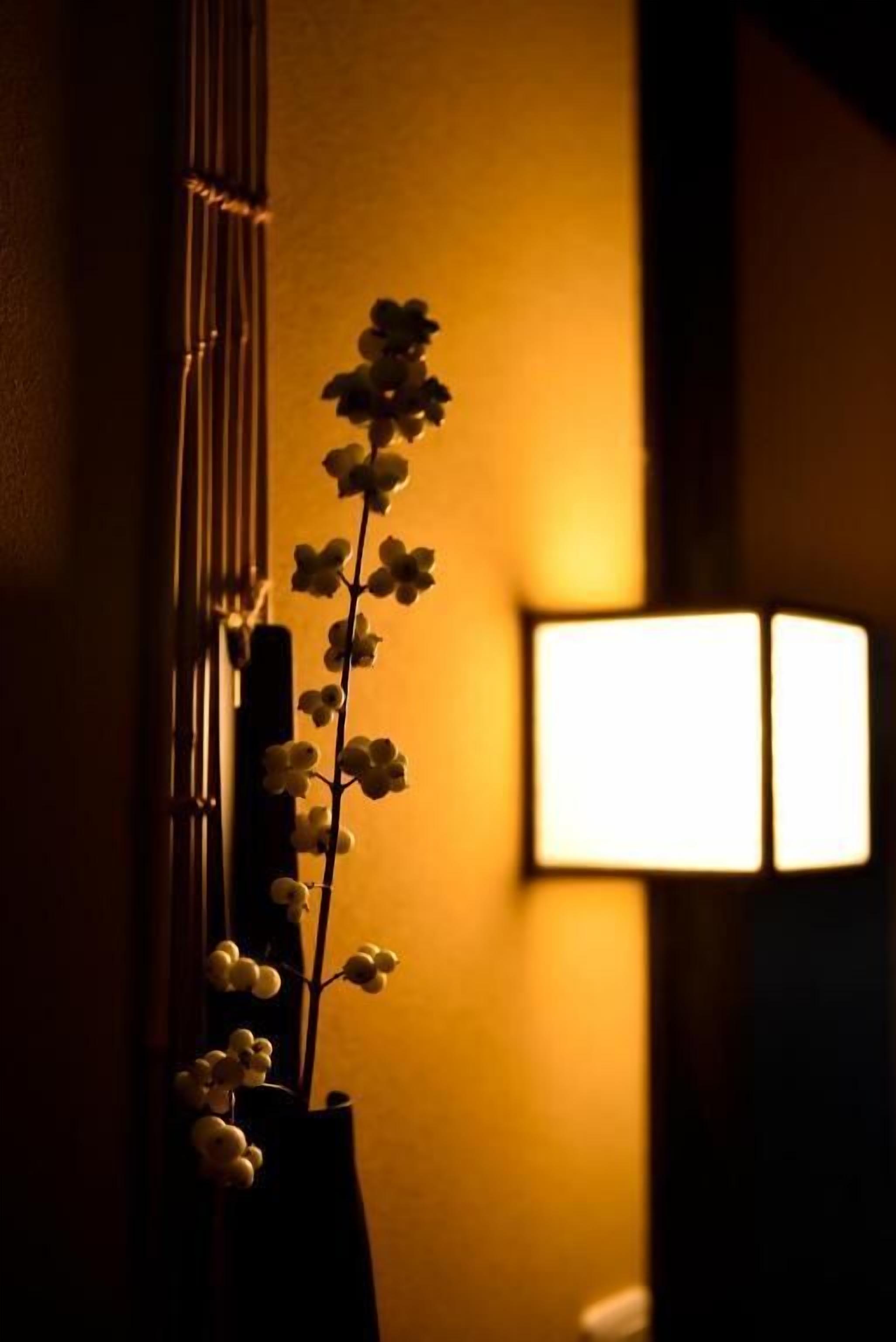 Ein Zimmer mit einer Wandlampe und einer Blumenvase.