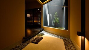 A hallway with a large window, a small indoor garden, and a bookshelf. - Miro Hachijo Genmachi BeTei (Kyoto)