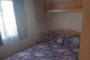 Quarto com cama, mesa de cabeceira e cabeceira.
