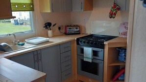 A compact kitchen with a sink, a toaster, a stove, and a window with a view of the outside. - 3Bed-Sleeps6-Pet Friendly-FamilyFriendly (Mablethorpe)