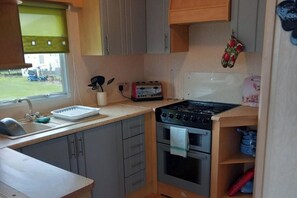 Eine kompakte Küche mit Spüle, Toaster, Herd und einem Fenster mit Blick ins Freie.