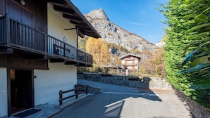 A building with a balcony, a stone wall, and a mountain in the background.