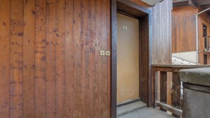 Eine Holztür mit der Nummer 12, einem kleinen Lichtschalter und einem Betonboden.