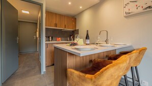 Eine moderne Küche mit einer zentralen Kochinsel, Holzschränken und einer Bar mit zwei Hockern.