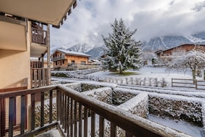 A snow-covered landscape with a wooden building and a snow-laden tree in the foreground.