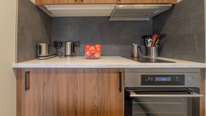 Eine moderne Küche mit Holzschränken, einer Edelstahl-Dunstabzugshaube, einem eingebauten Backofen und einer Schüssel Äpfel auf der Arbeitsplatte.
