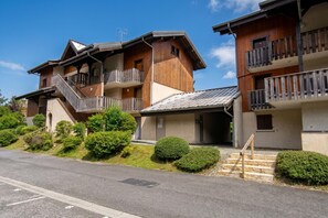 A multi-story wooden building with balconies, a covered entrance, and a clear sky.