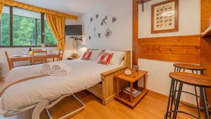 Ein Zimmer mit einem Bett, einem Schreibtisch, einem Stuhl, einem kleinen Tisch und einer Wand mit Dekoration.